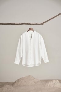 Home White shirt displayed on a branch, showcasing minimalist fashion aesthetics and natural style.