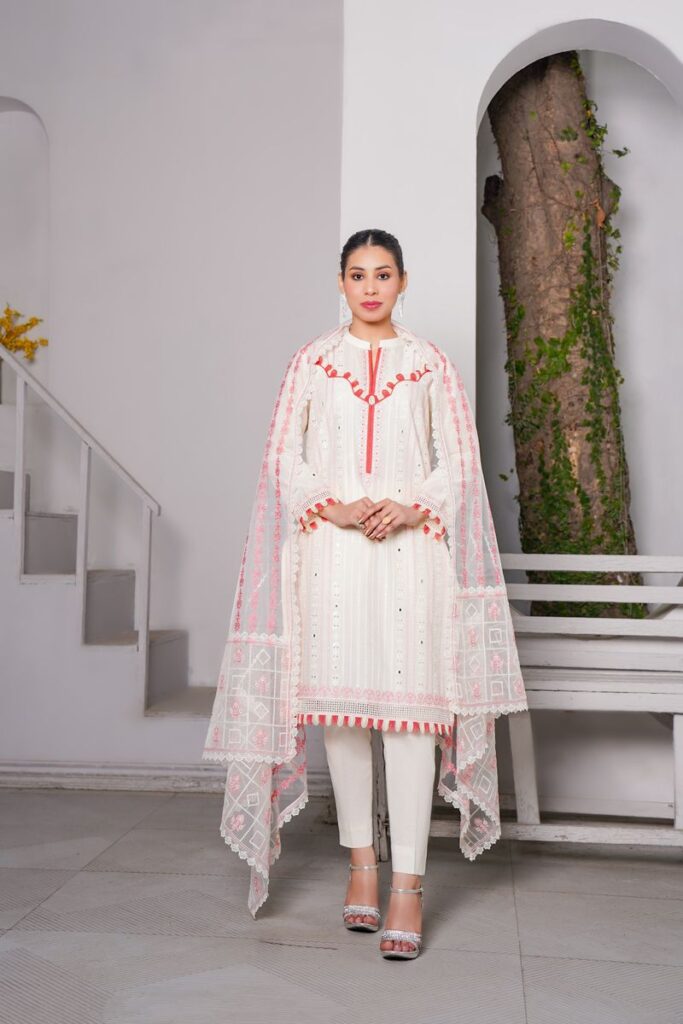 Chic portrait of a woman in a traditional white dress with red accents, posing indoors.